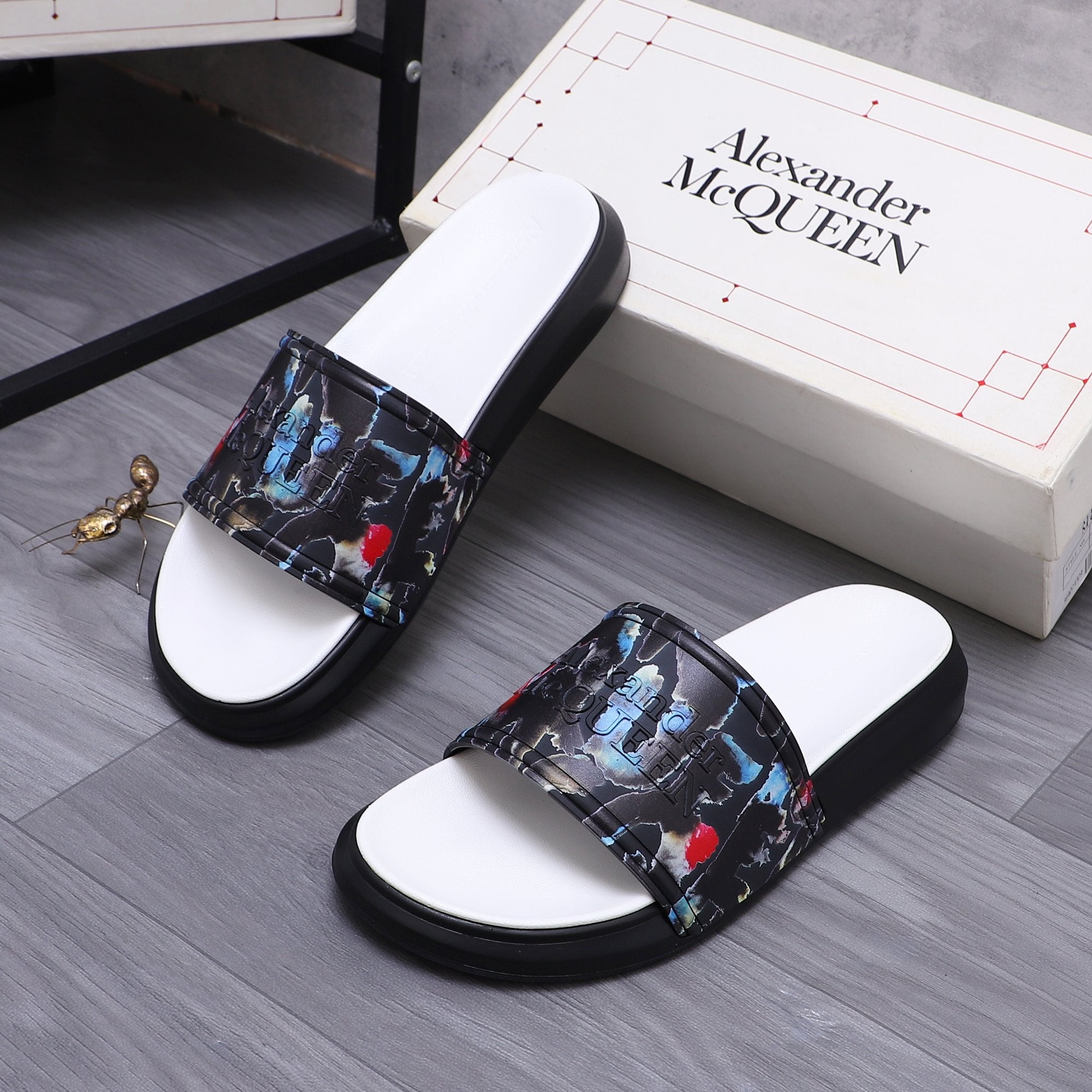 Black slide sandals with white footbeds and multicolor abstract strap panel