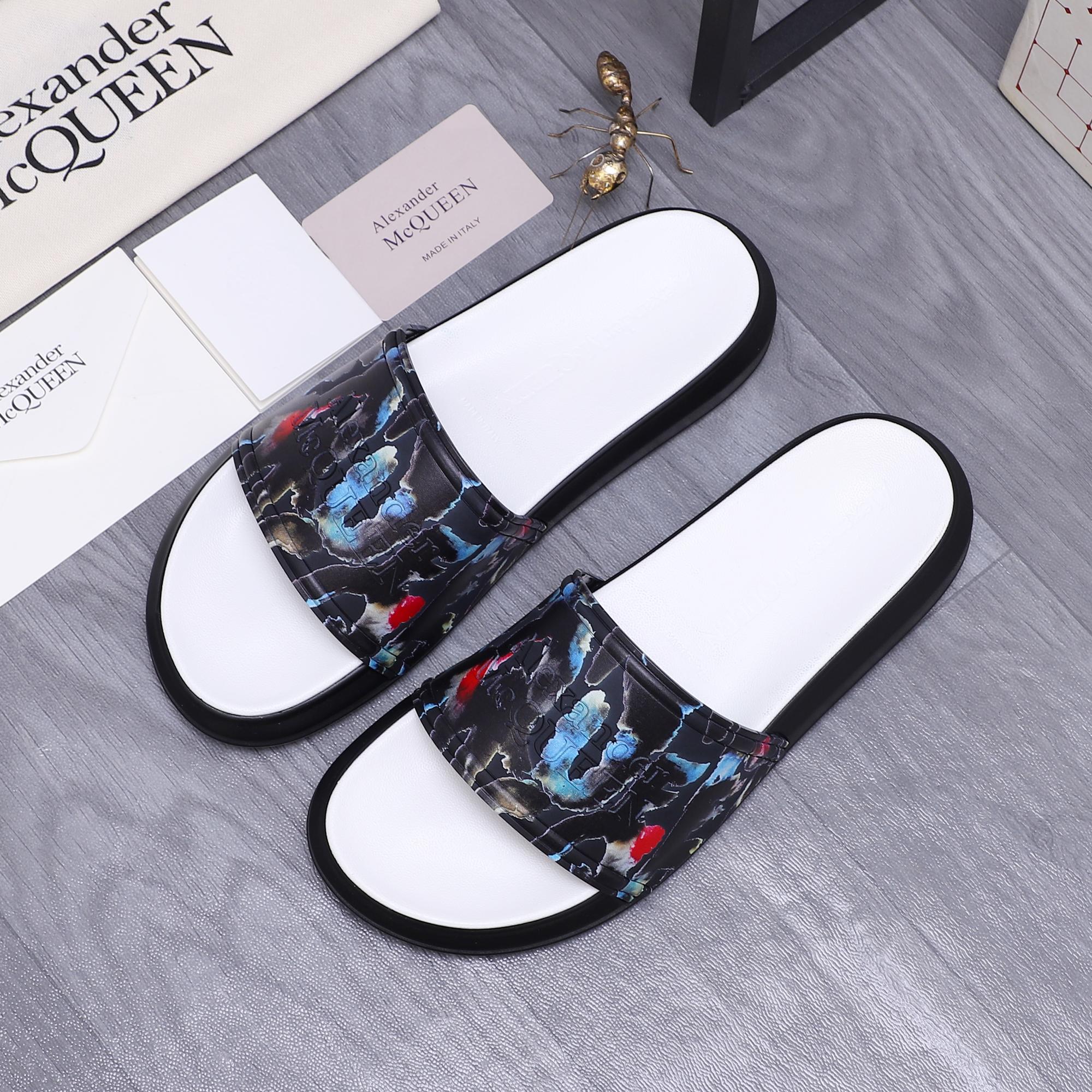 Pair of black slide sandals with white footbeds and colorful abstract strap print