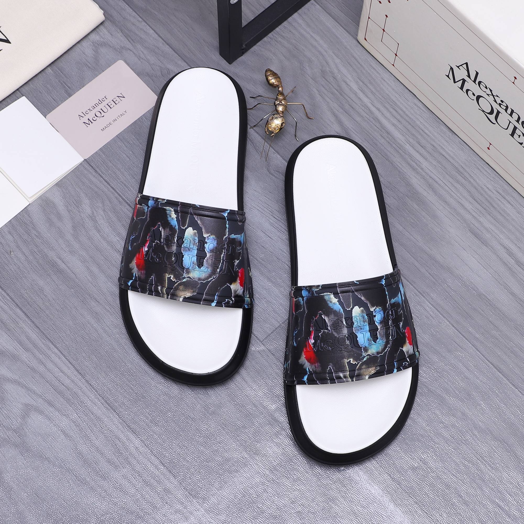 Black slide sandals with white footbeds and multicolor abstract print across straps