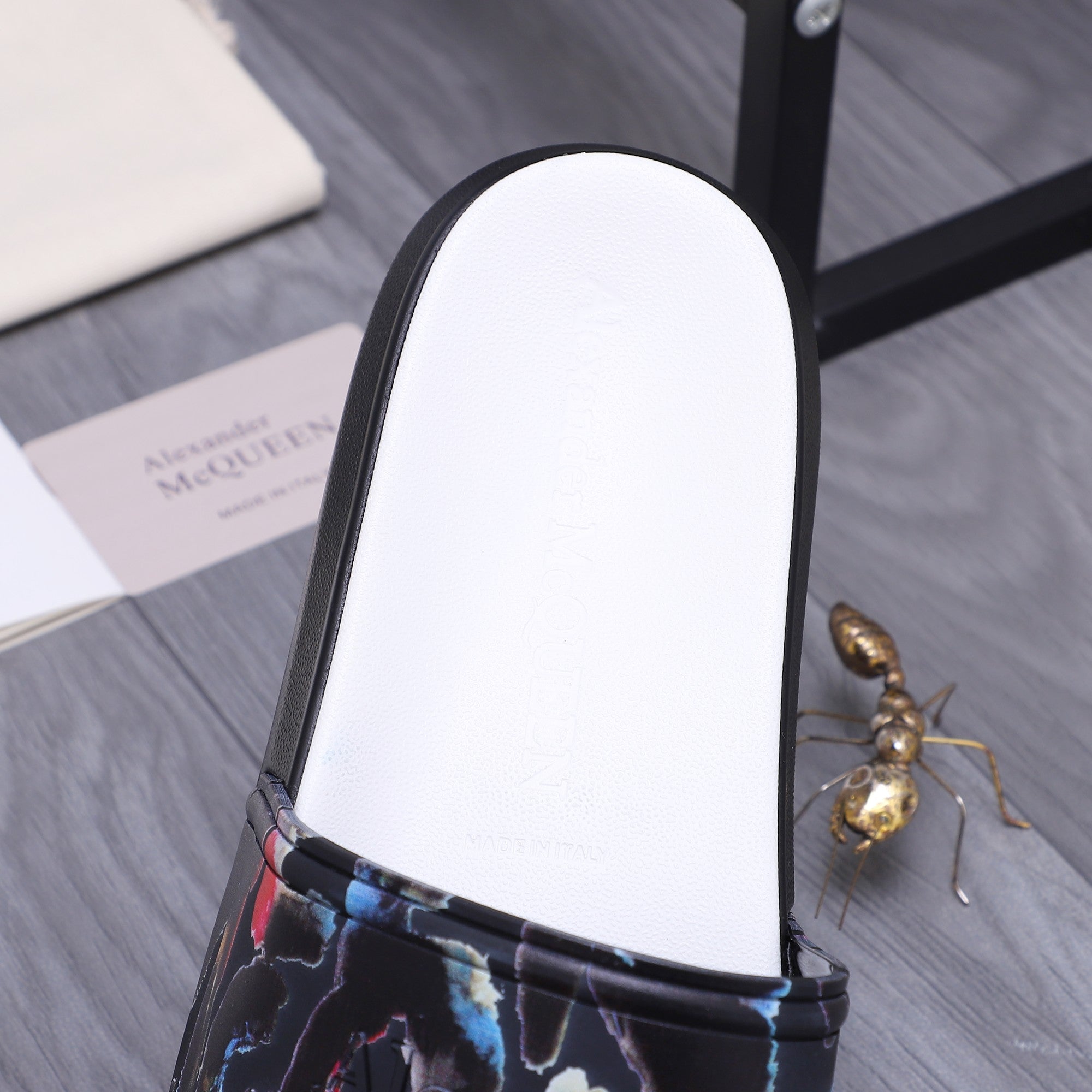 Close-up of black slide sandal with white footbed and multicolor abstract strap