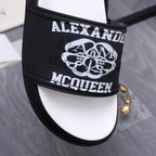 Alexander McQueen slide sandal strap close-up, black with bold logo print
