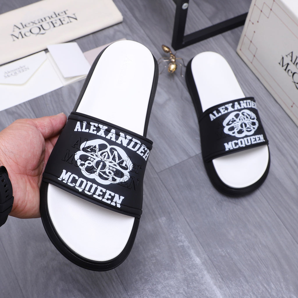 Alexander McQueen slide sandals, black logo strap over white footbeds, hands holding