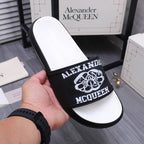 Alexander McQueen slide sandal held up, white footbed with black logo strap