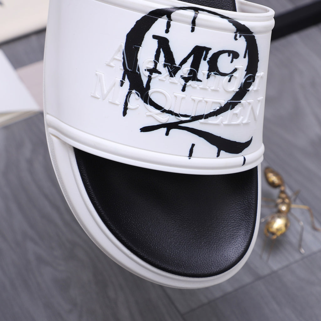Alexander McQueen slide sandal close-up, white strap with MC logo graffiti print