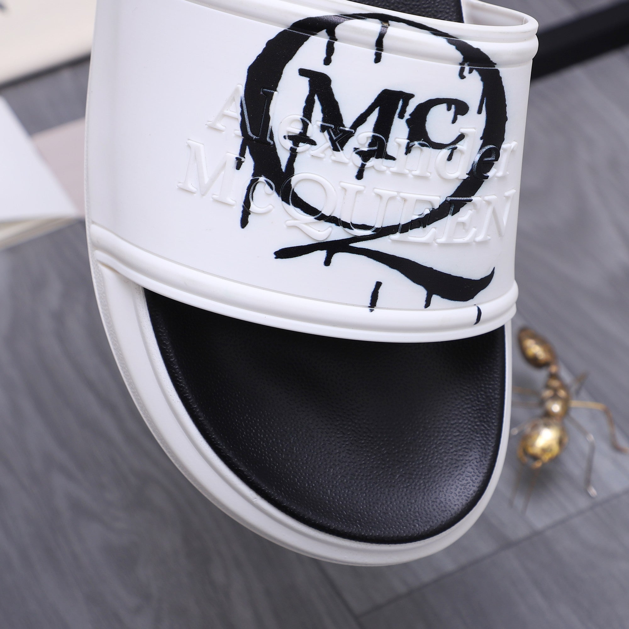 Alexander McQueen slide sandal close-up, white strap with MC logo graffiti print
