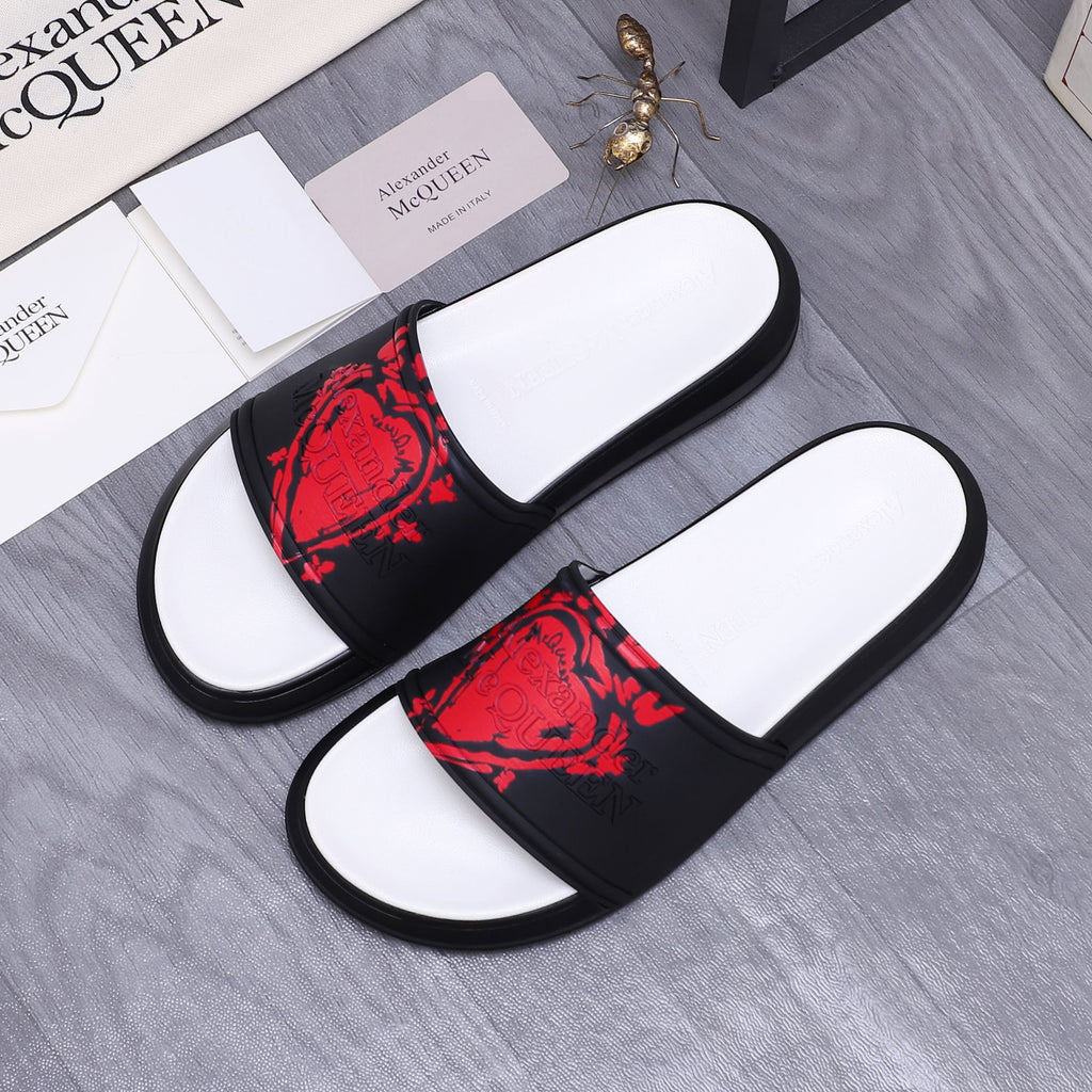 Black slide sandals with red graphic print on the strap and white molded footbed