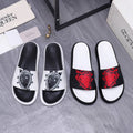 Slide sandals set with white footbeds and decorative black straps in red or white
