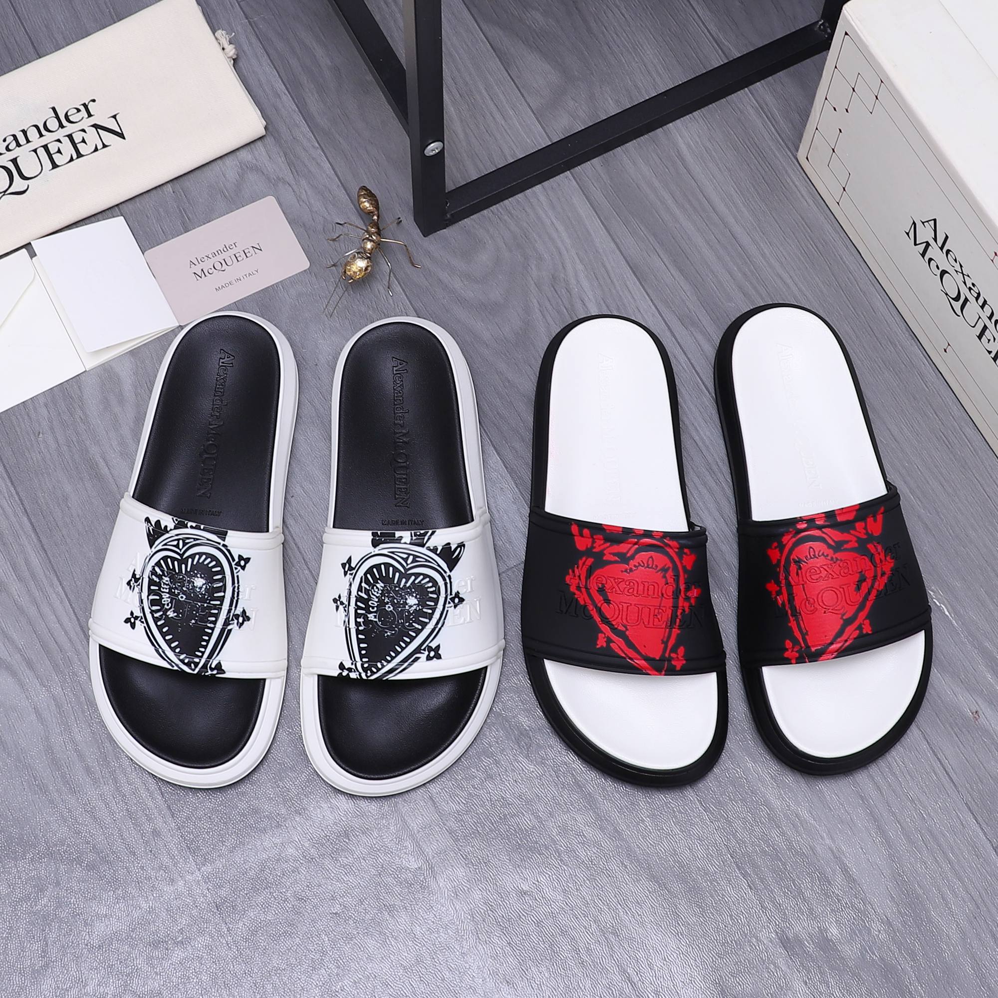 Alexander McQueen slide sandals, white and dark pairs with graphic emblems