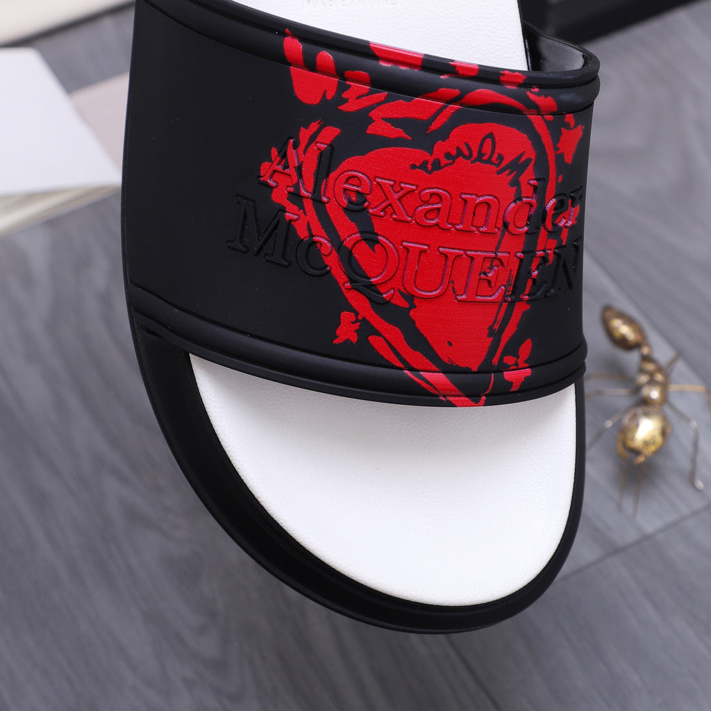 Close-up of black slide sandal strap with red graphic design and black trim edge