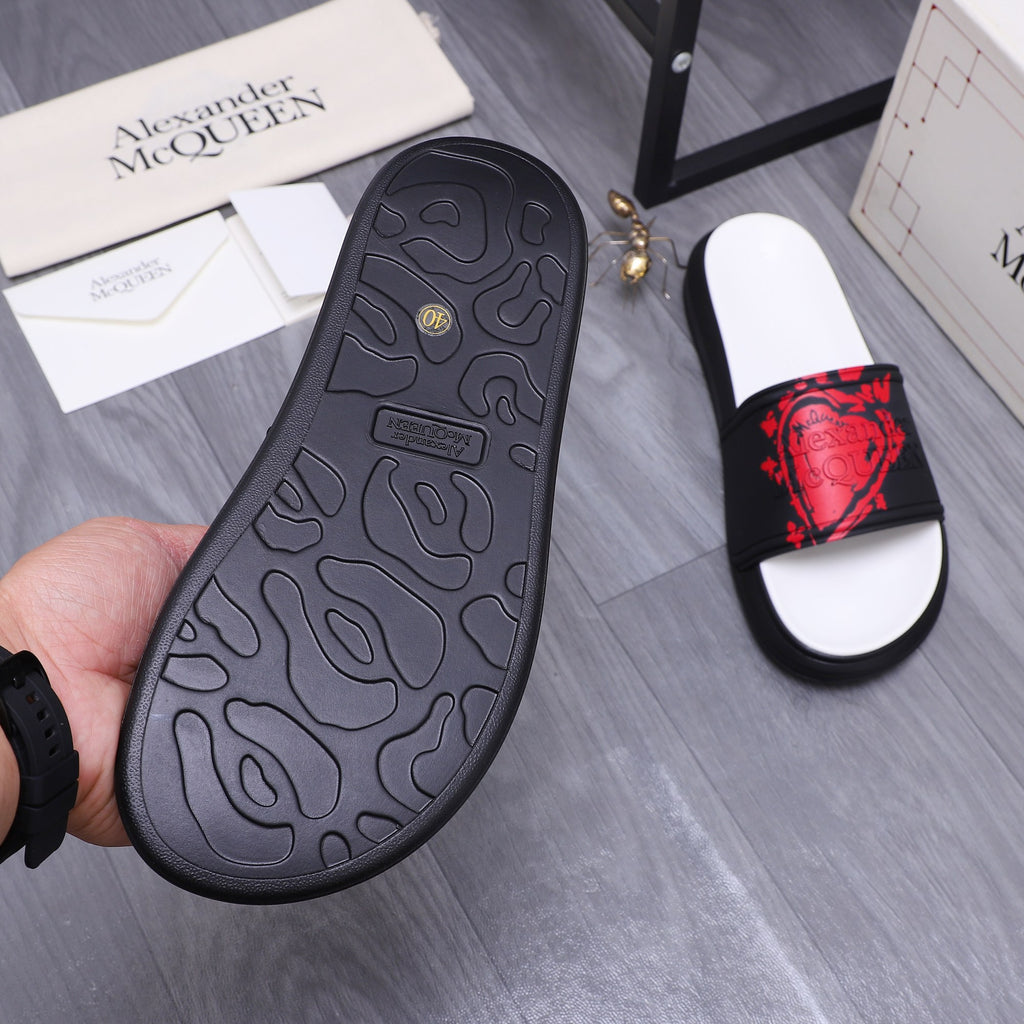 Black rubber slide sandal outsole with textured pattern and red-printed strap