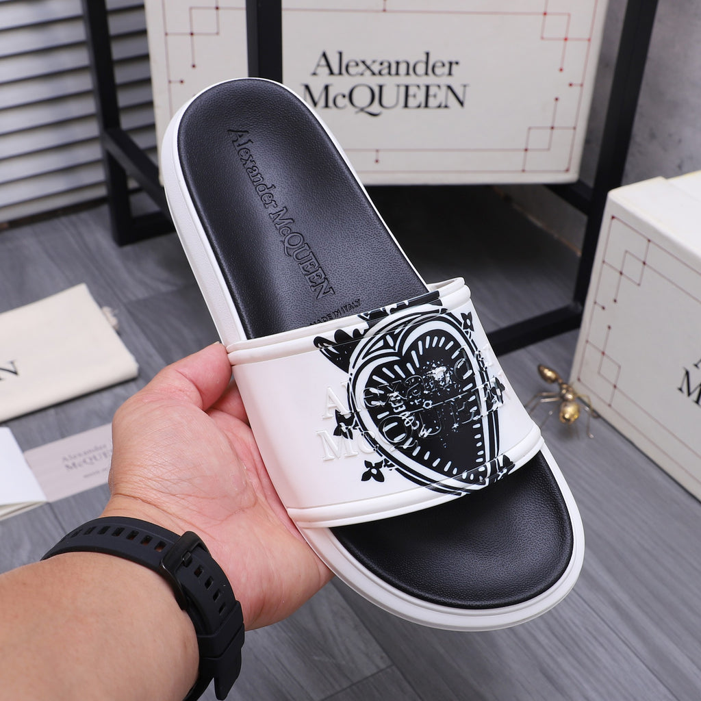 Alexander McQueen slide sandals, white strap with black crest graphic, in hand view