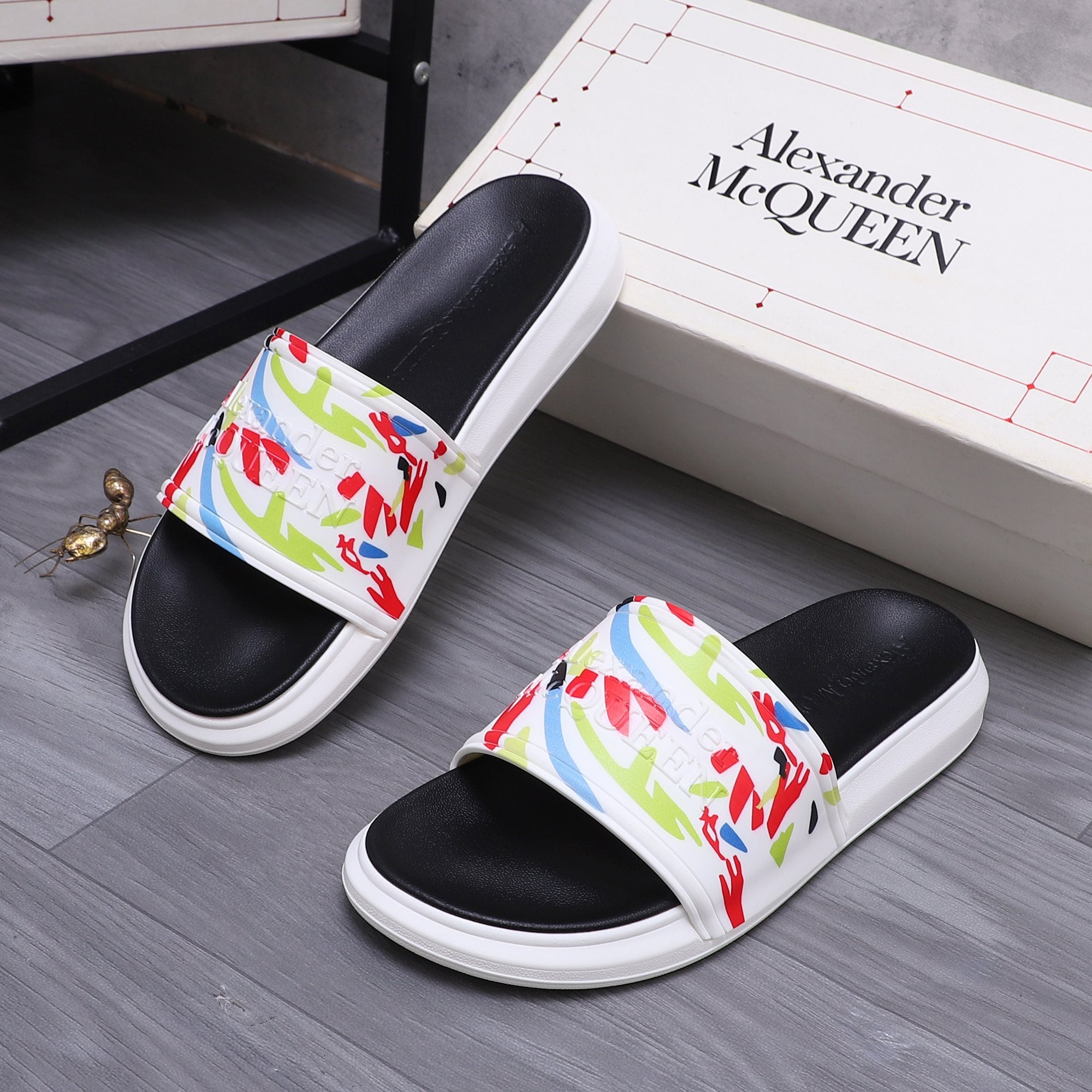 Black slide sandals with white soles and bright graffiti-print upper band.