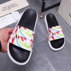 Black slide sandals on hand display, multicolor graffiti band and white sole.