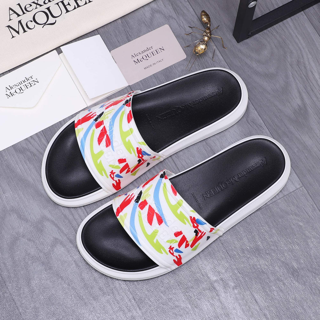 Pair of black slide sandals with white soles and multicolor graffiti-style straps.
