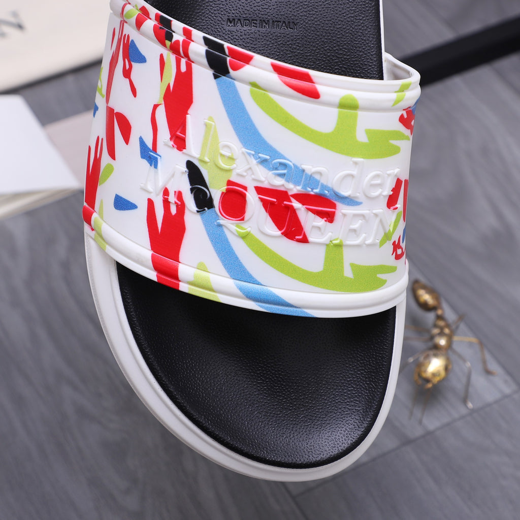 Close-up of black slide sandal with red, blue, and green graffiti print band.