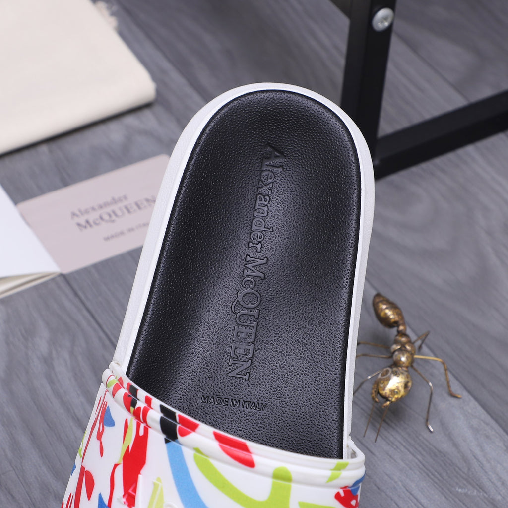 Black slide sandal showing footbed and multicolor graffiti band with white edge.