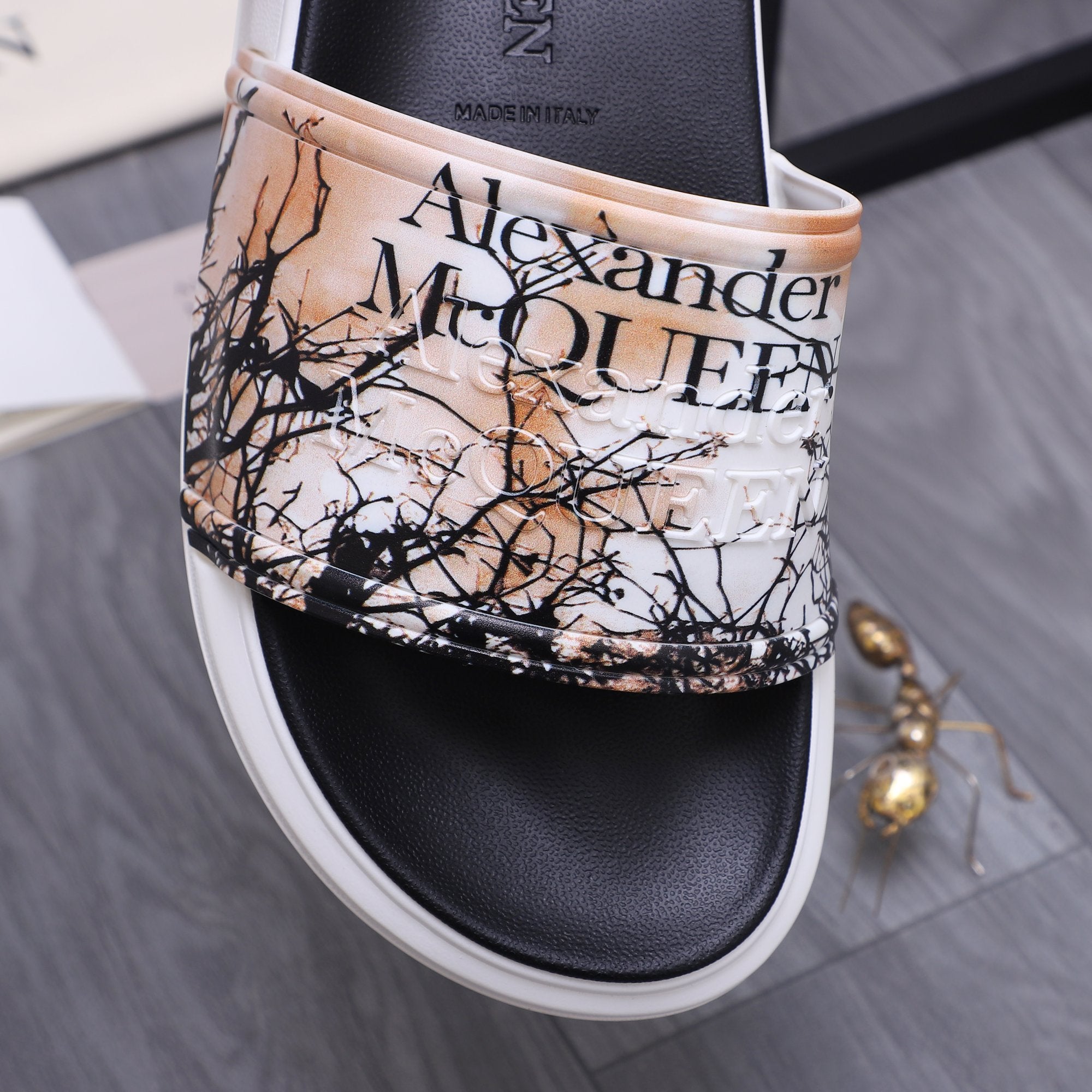 Alexander McQUEEN slide sandal upper close-up with beige band, black graphic text print