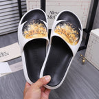 Alexander McQueen slide sandals, white straps with gold print over black footbeds.