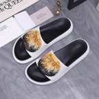 Alexander McQueen slide sandals, black footbeds, white straps, gold floral print.