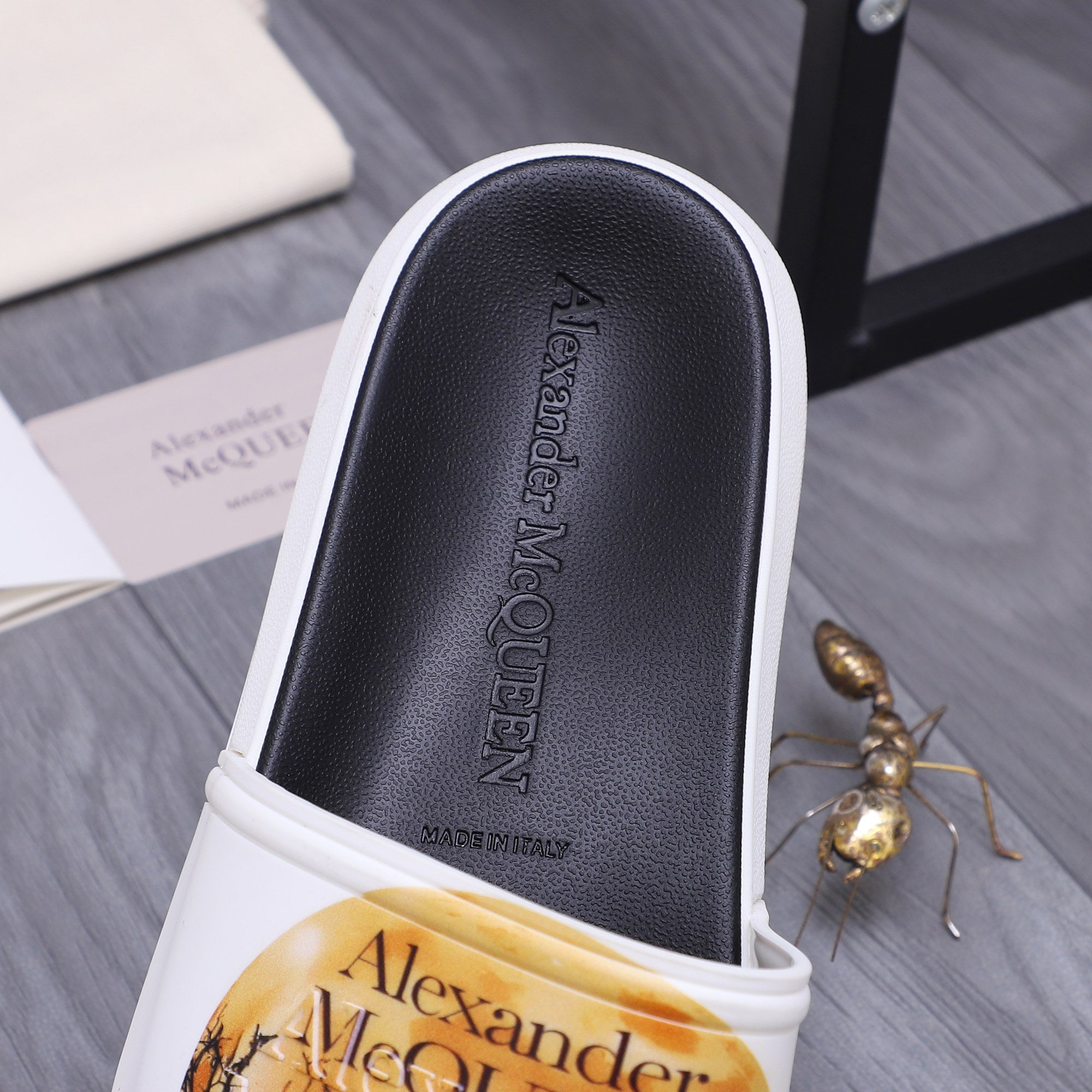 Alexander McQueen slide sandal footbed close-up, black insole with brand embossing.