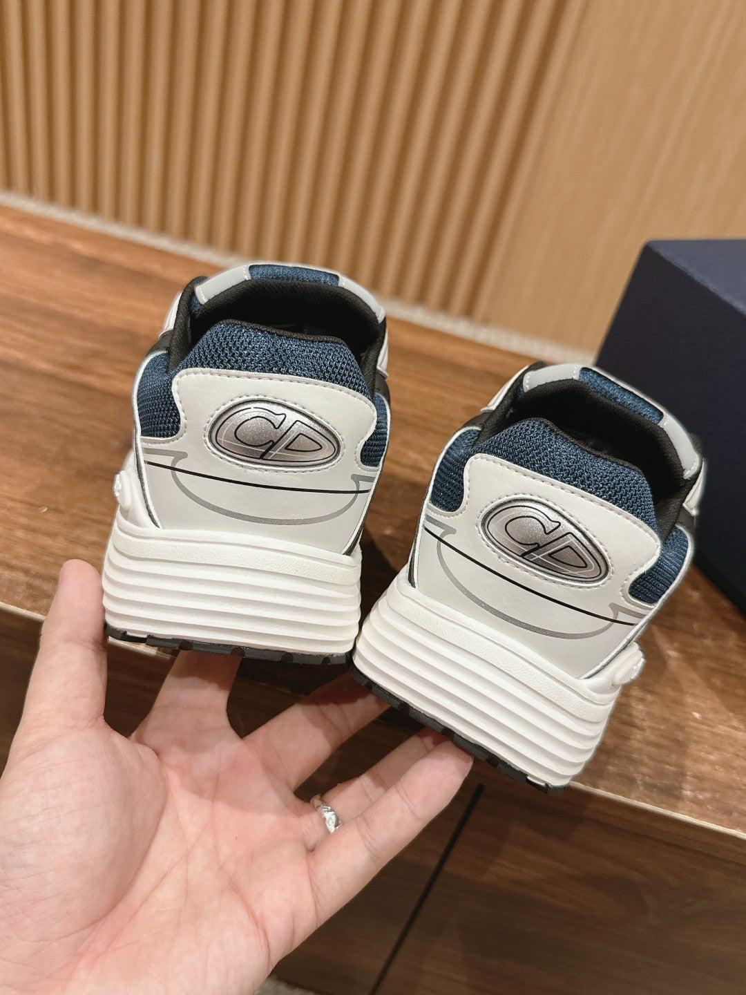 Back view of dark blue and white sneakers with logo on the heel and lace panel
