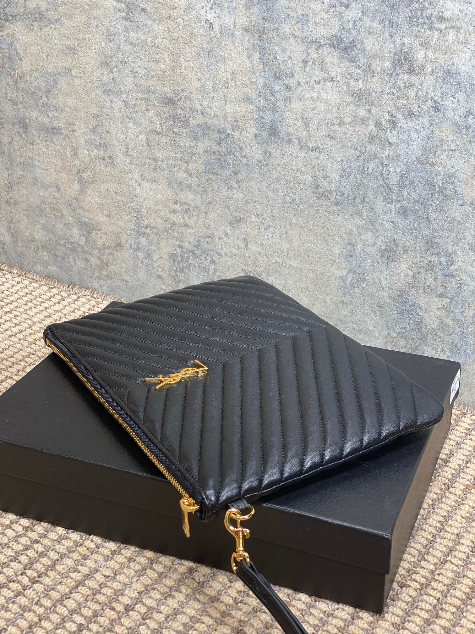 Dark quilted Saint Laurent clutch with gold-tone zipper and corner logo