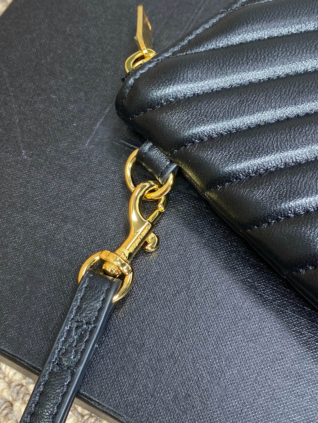 Gold-tone chain and ring on dark leather clutch zipper edge