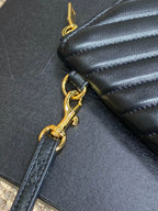 Gold-tone chain and ring on dark leather clutch zipper edge