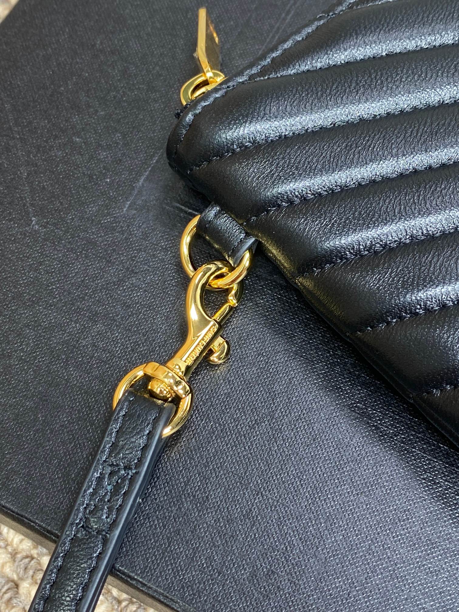 Gold-tone chain and ring on dark leather clutch zipper edge