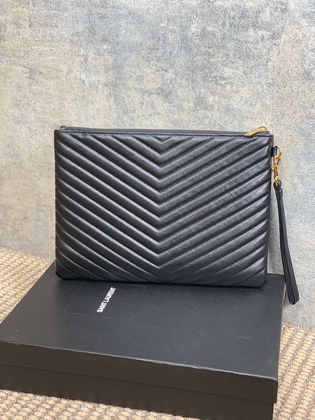 YSL small quilted clutch bag with chevron pattern, gold logo, and side wrist strap