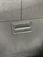 Leather branding patch on dark Saint Laurent clutch front panel