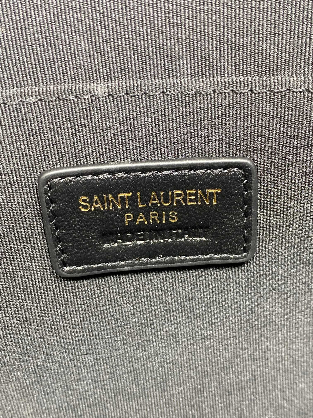 SAINT LAURENT PARIS logo label on the dark quilted bag exterior