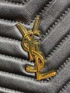 Gold YSL logo hardware on textured dark quilted bag surface