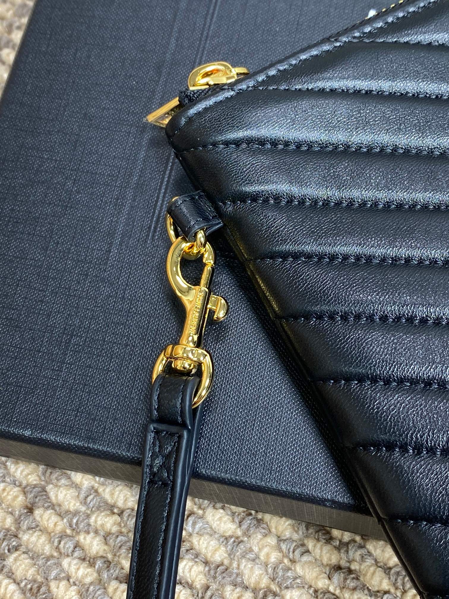 Close-up of gold zipper hardware and attached dark blue chain strap