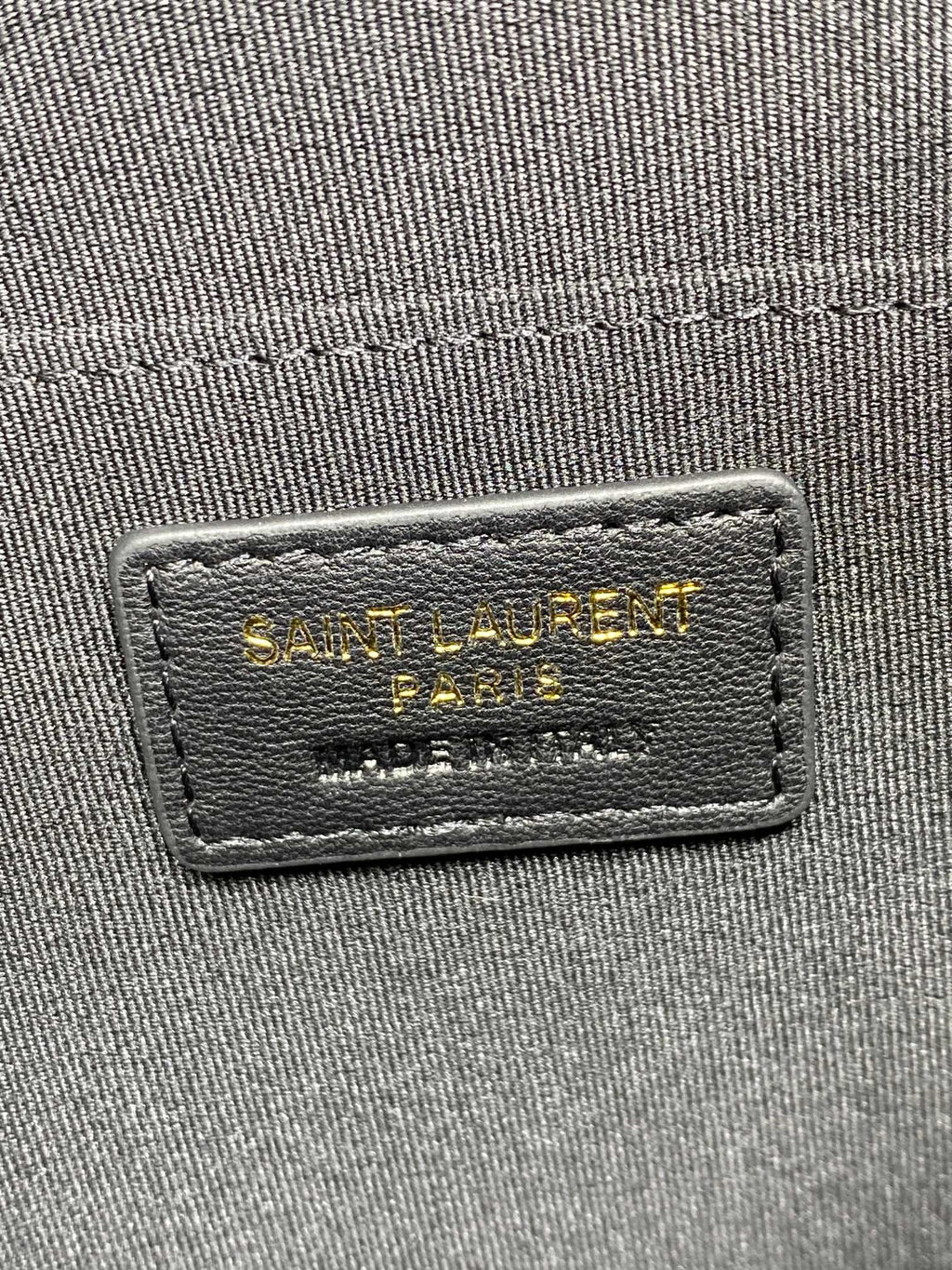 Rectangular interior brand label on dark fabric inside the clutch bag