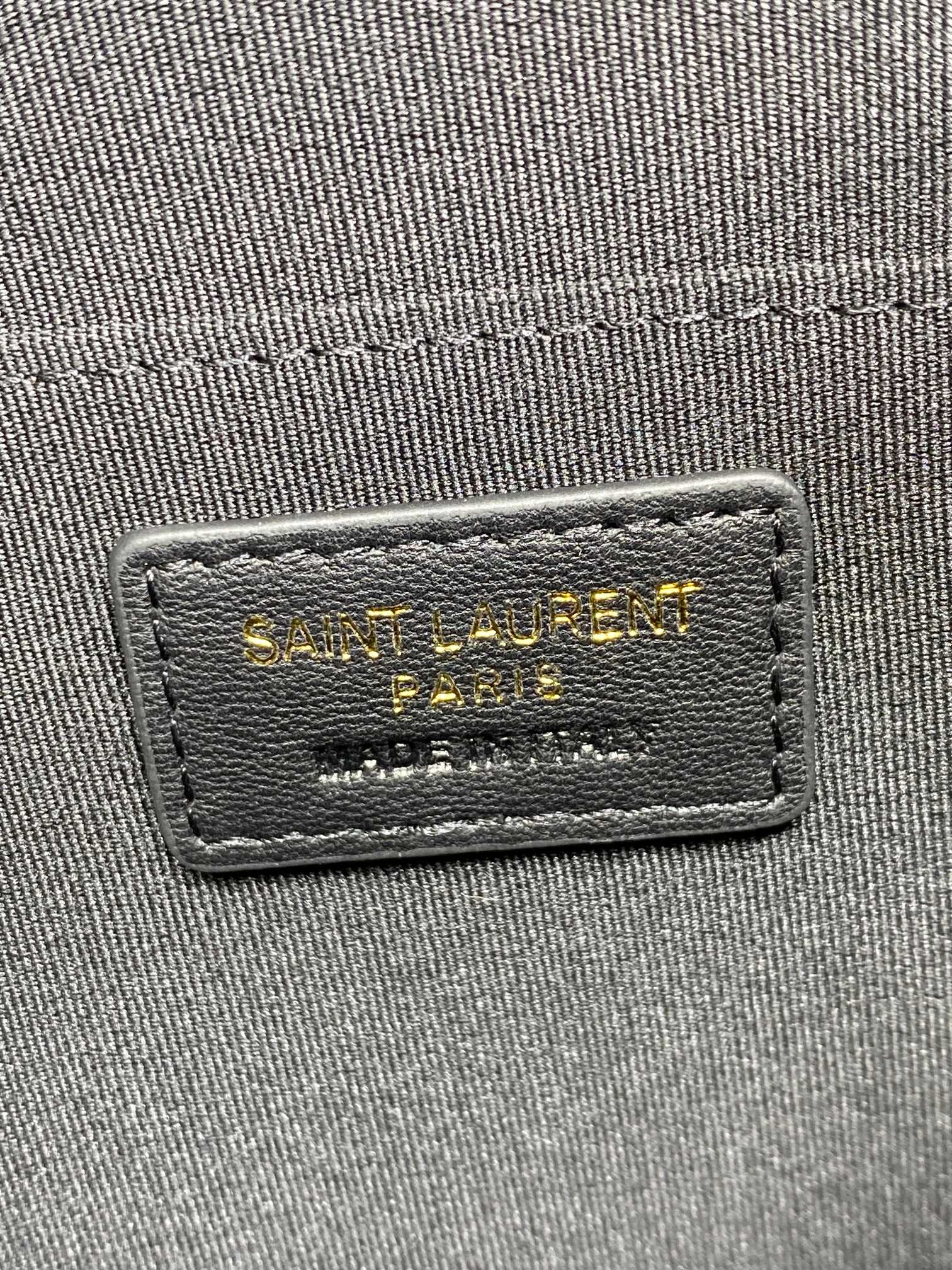 Rectangular interior brand label on dark fabric inside the clutch bag