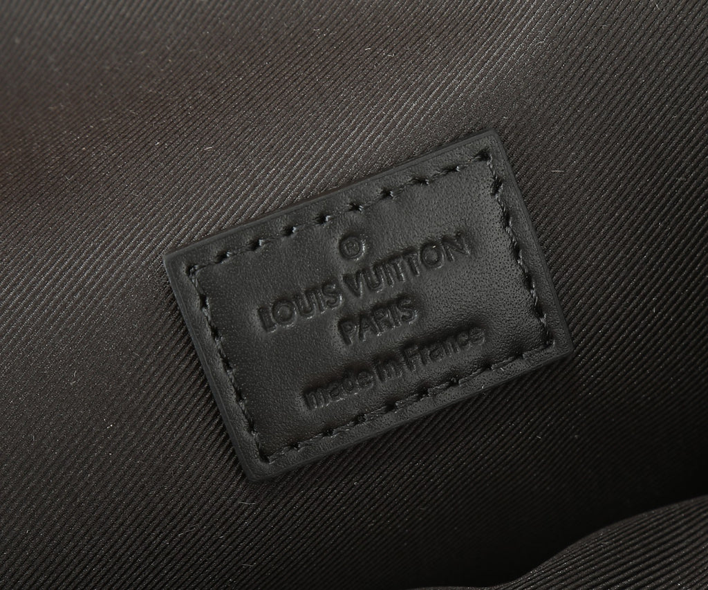 Louis Vuitton leather label close-up on dark strap end with embossed text