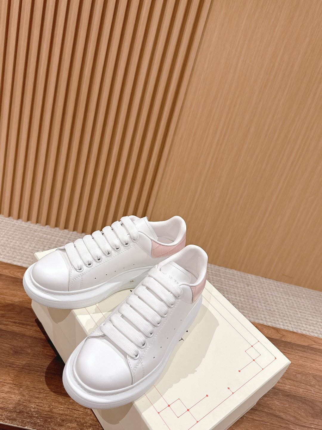 White leather low-top sneakers on light box, lace-up design