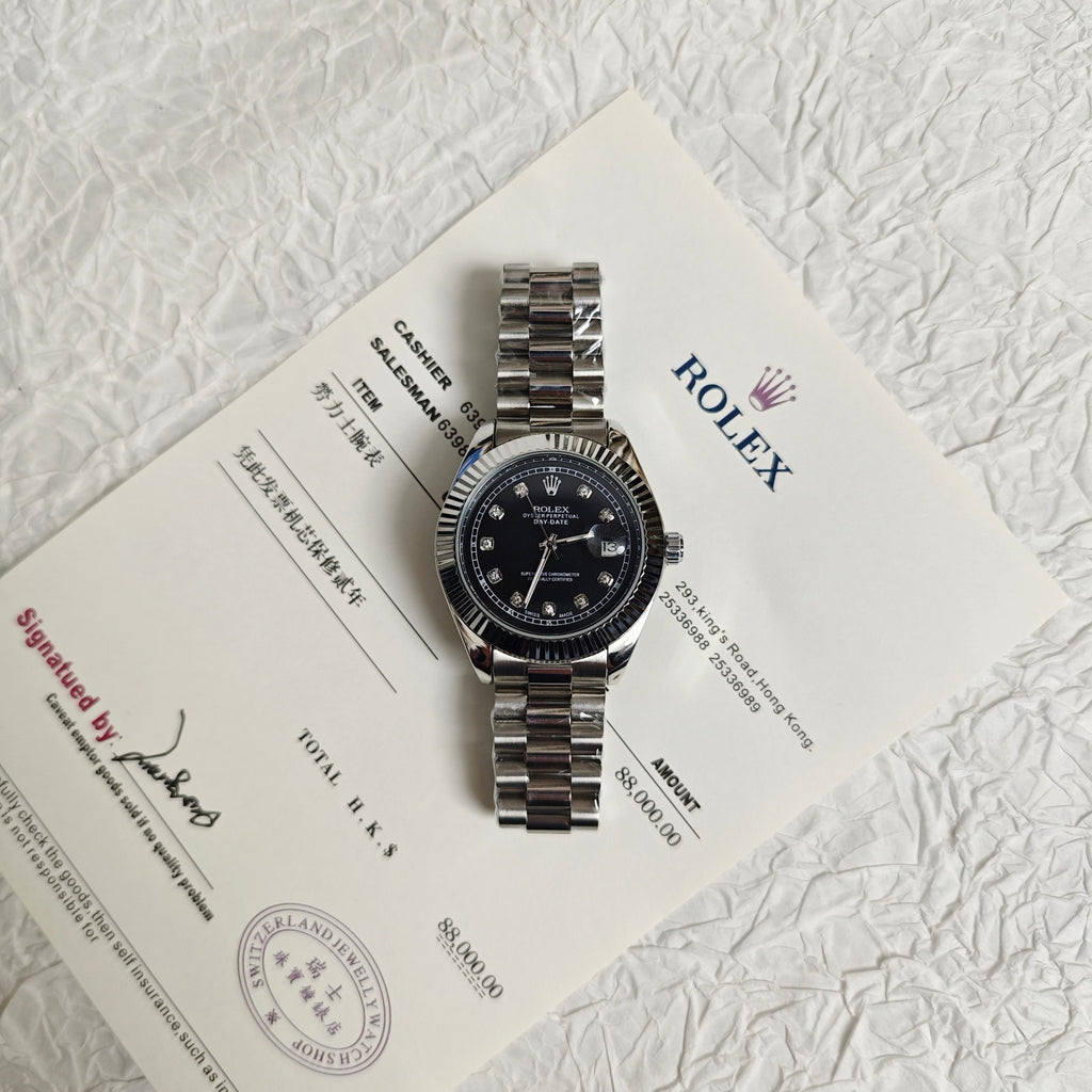 Rolex wristwatch with black dial on paperwork, silver steel bracelet
