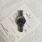 Rolex wristwatch with black dial on paperwork, silver steel bracelet