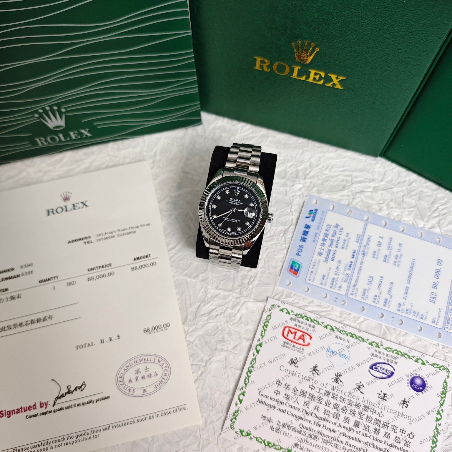 Rolex wristwatch with black dial and steel bracelet beside certificates and documents