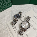 Rolex wristwatch pair on paperwork: dark dial watch and silver dial watch