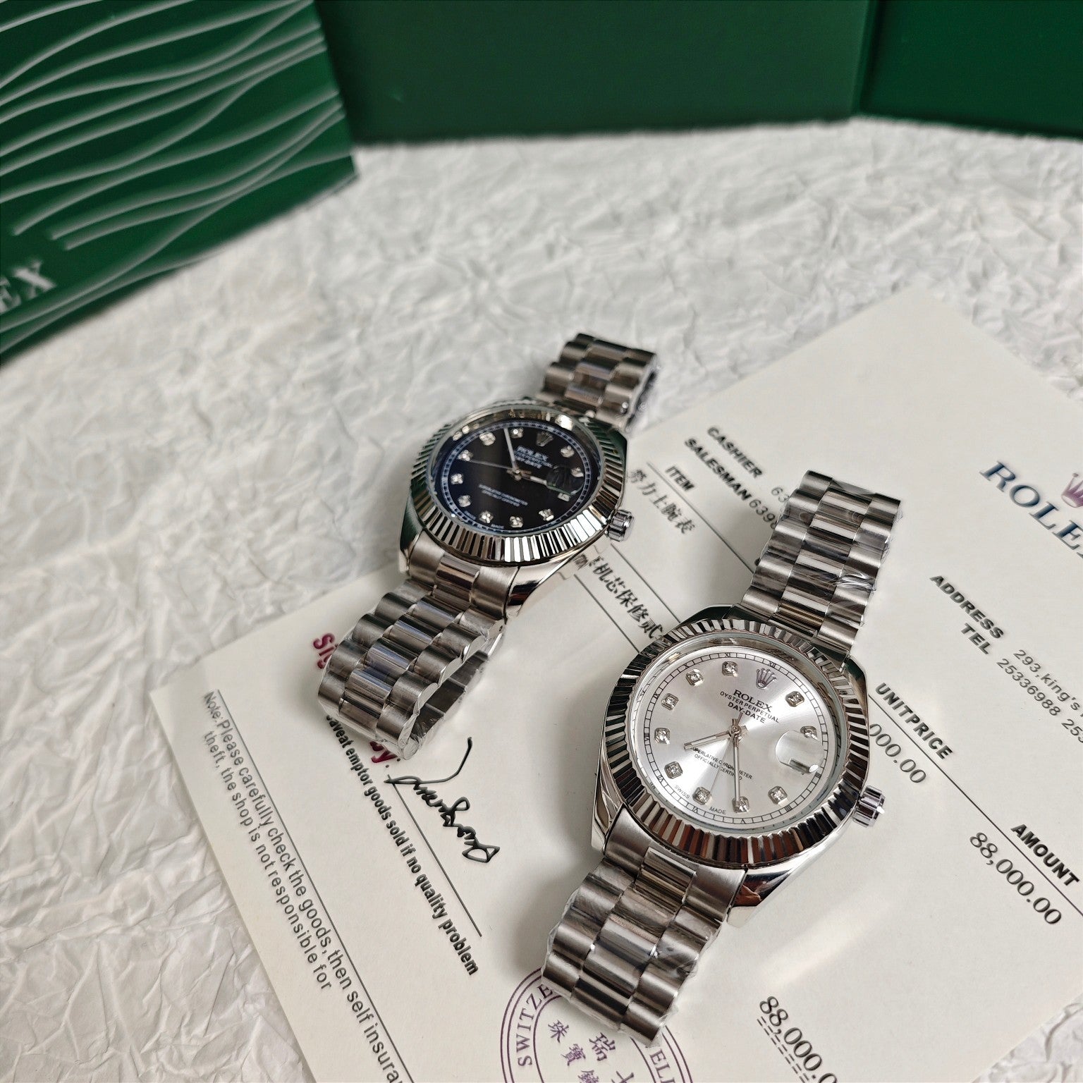 Rolex wristwatch pair on paperwork: dark dial watch and silver dial watch