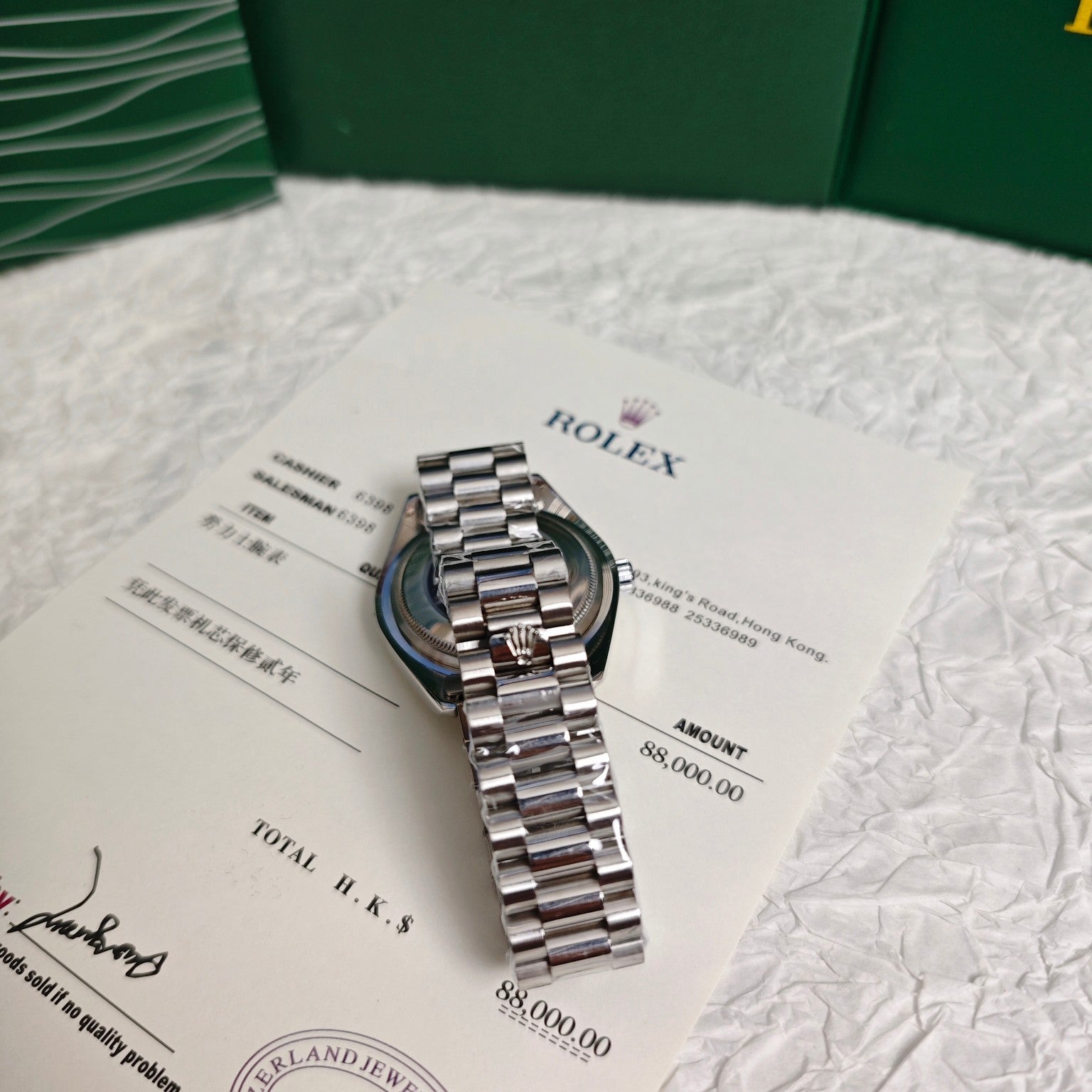 Rolex steel bracelet watch on documents with green packaging behind