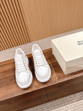 Pair of white lace-up sneakers with thick rubber sole and stitched overlays