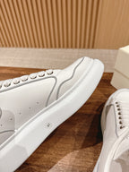 White lace-up sneakers with studded trim along the side and textured sole