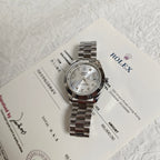 Rolex wristwatch on paperwork with silver dial and steel bracelet, side view