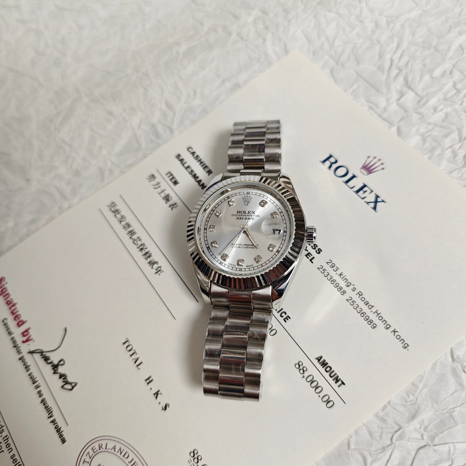 Rolex wristwatch on paperwork with silver dial and steel bracelet, side view