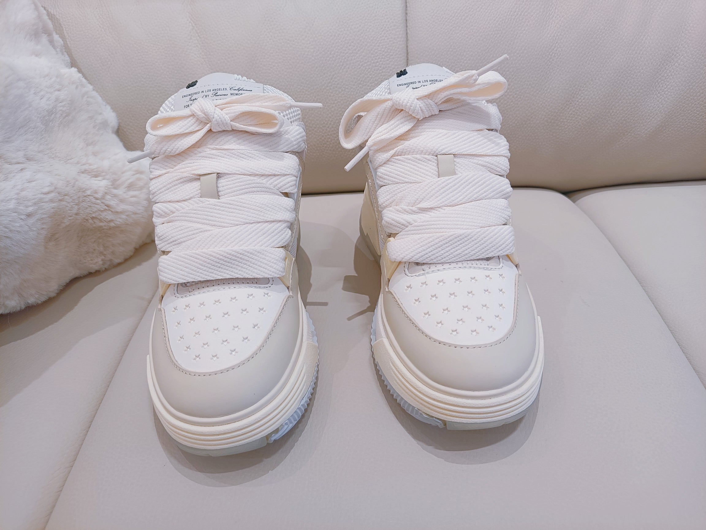 White high-top sneakers with lace-up closure and textured toe cap; back view