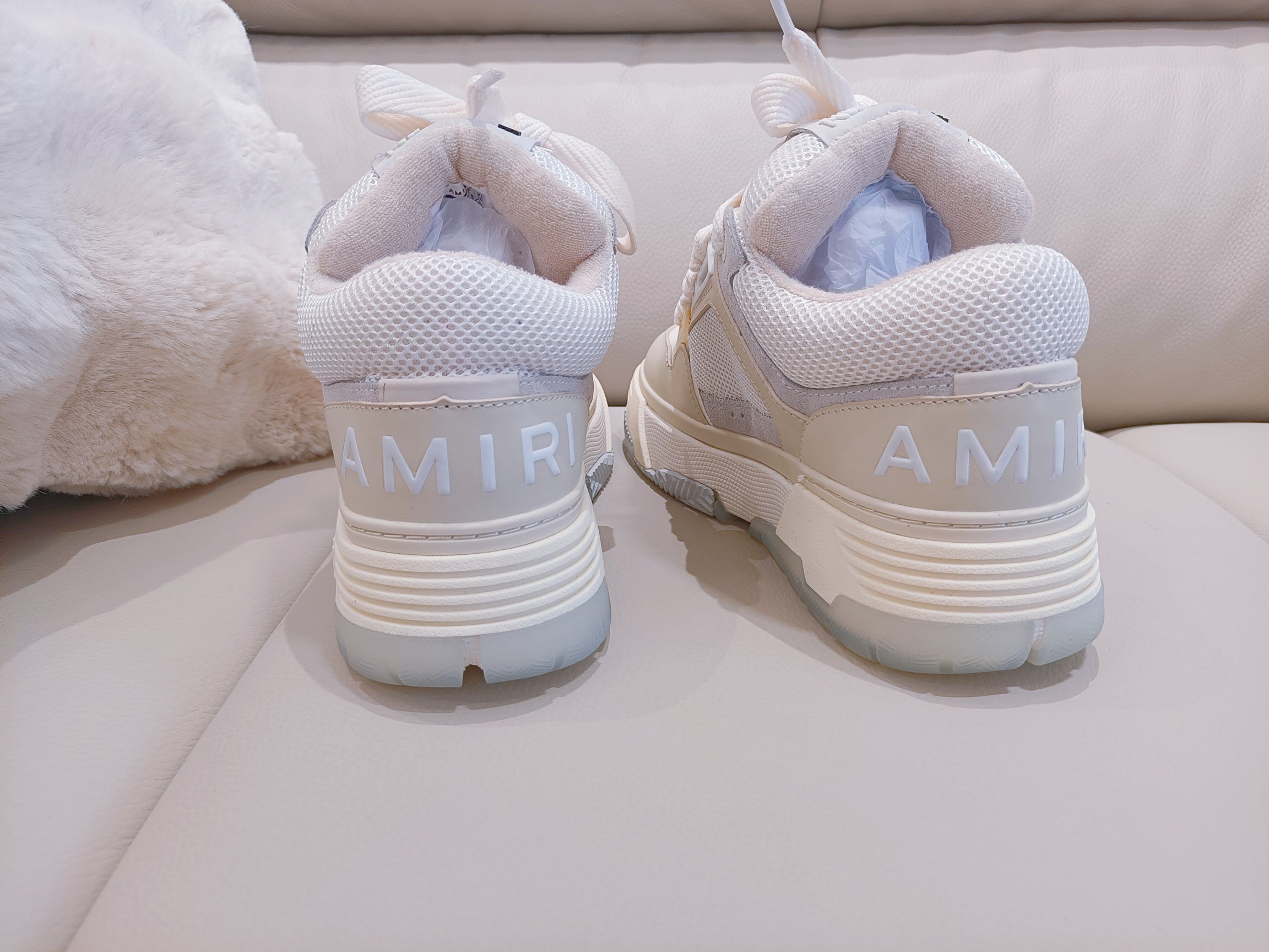 Light beige sneakers with white laces and AMIR heel logo, rear view